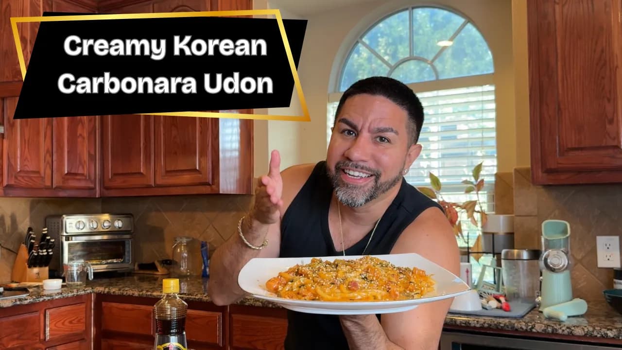 SuperZydan holding a plate of creamy Korean carbonara udon in his kitchen
