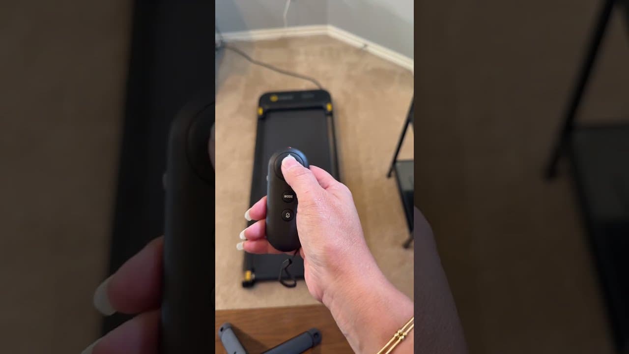 Holding the UREVO walking pad's remote above the walking pad